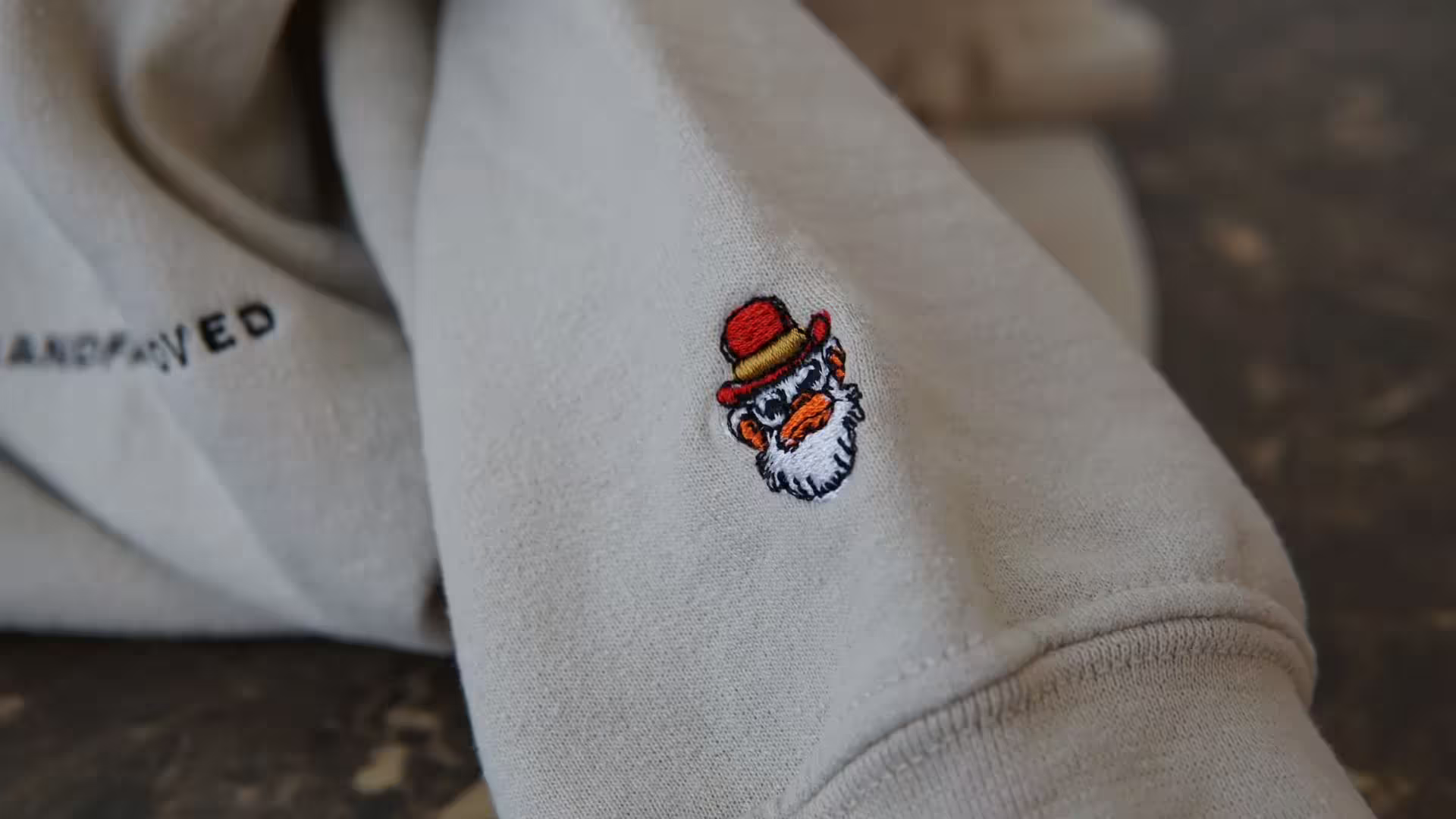 Logo on left sleeve of sand sweater